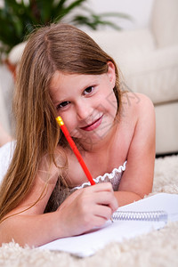在客厅用铅笔和记本微笑的年轻女孩看着你美丽的高清图片素材