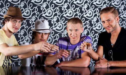 四个有魅力的人在迪斯科俱乐部的鸡尾酒派对喝图片