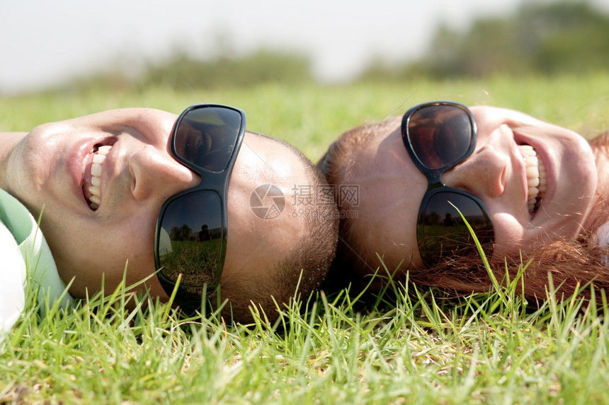 一对年轻夫妇躺在草坪上微笑图片