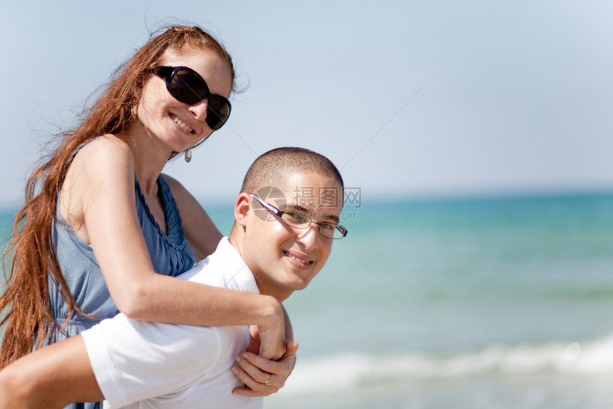 年轻男人的肖像带着女友在海滩上搭便车图片