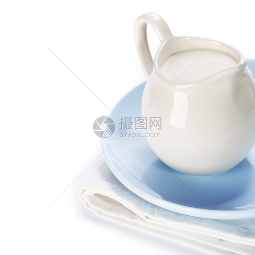 蓝色盘子上加牛奶的白色陶瓷罐图片