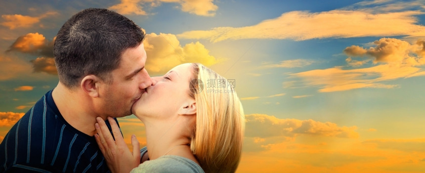 在日落的天空里浪漫爱情中亲吻一对侣全景版图片