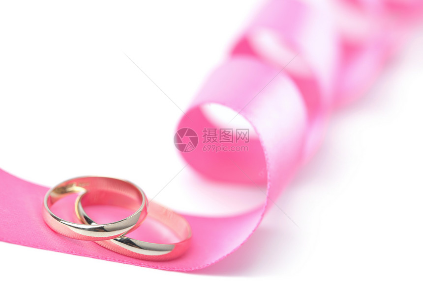 粉色丝带上的金结婚戒指被孤立图片