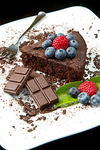 巧克力蛋糕白色盘子和黑背景上鲜莓果图片