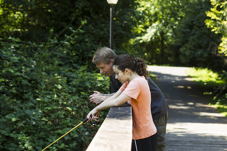 女孩和父亲在木桥上钓鱼图片