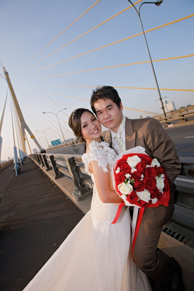 新娘和郎与美丽的玫瑰花束在公路桥上图片