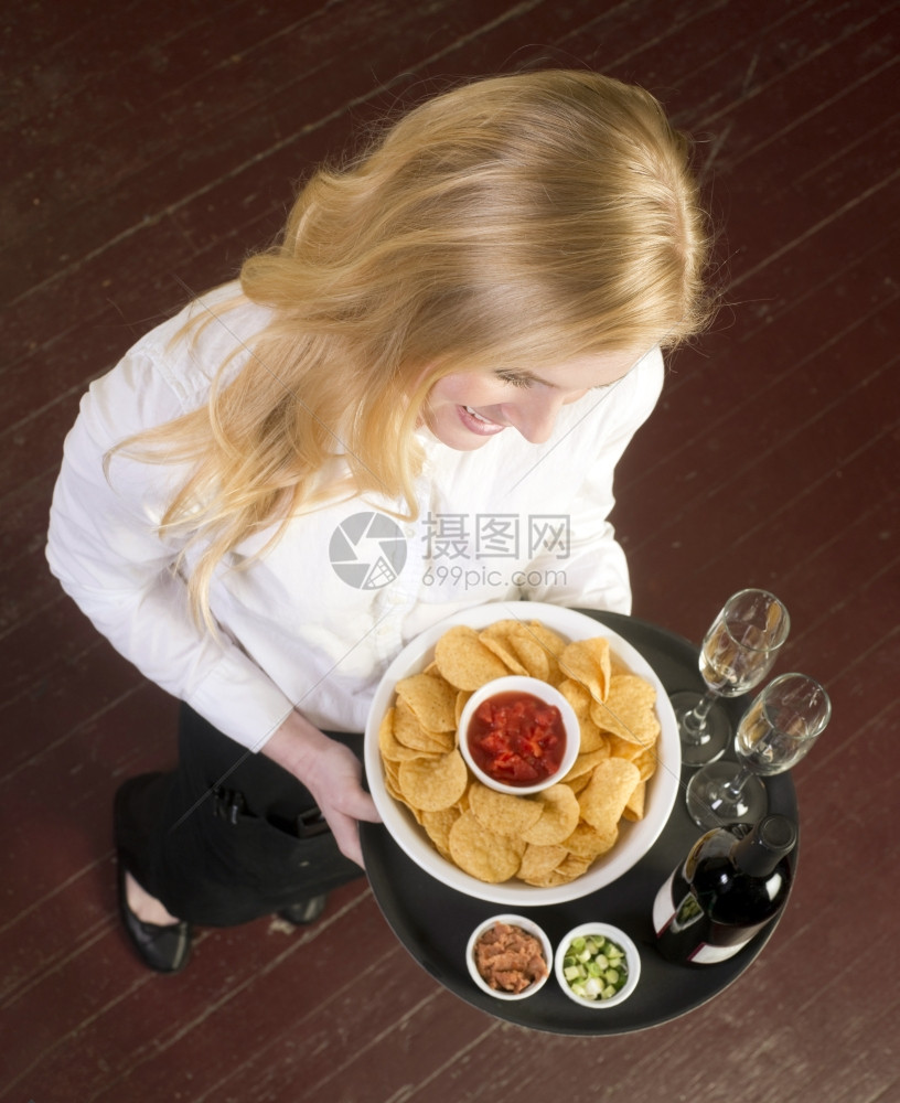 一个年轻迷人的女服务器带来酒和开胃食品托盘图片