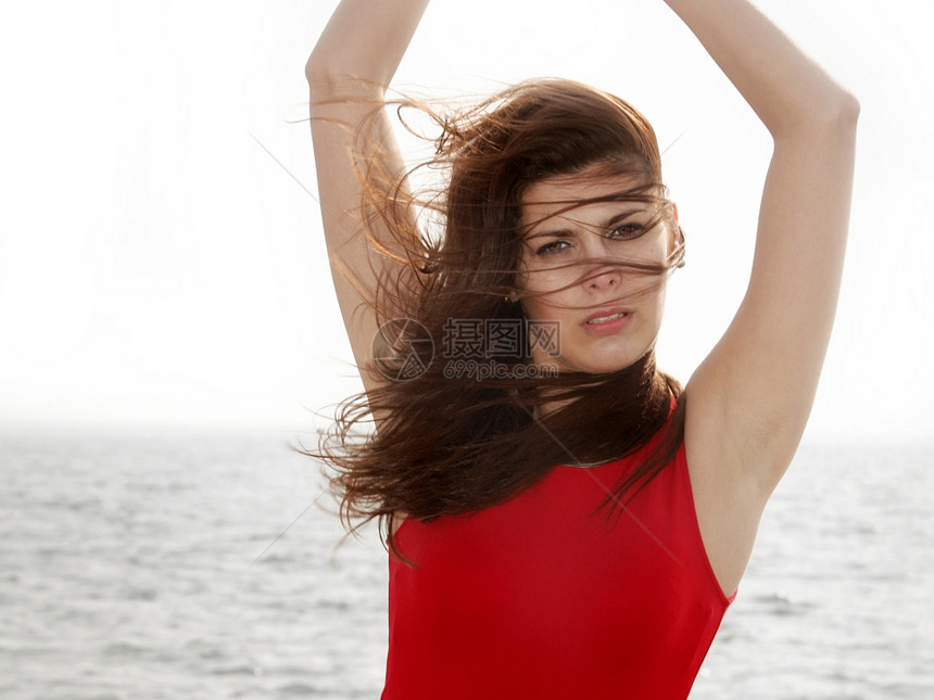 穿着红裙子的年轻女在码头早晨风吹着发暑假图片