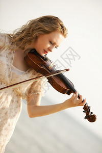 海滩上玩小提琴的金发女音乐情人的肖像爱音乐概念图片