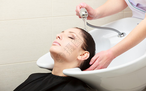 理发师洗客户头美容院的发女郎深色头发高清图片素材