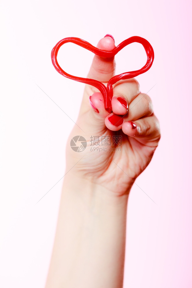女手握着情人红心爱的象征在粉红色情人节工作室拍摄图片