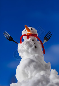 圣诞小雪人穿着蓝螺丝顶的帽子红色围巾和叉子户外冬季节特别蓝天空背景图片