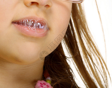 戴眼镜的有趣小女孩做有趣的唾液泡图片