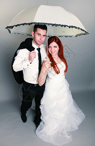 新郎和红发娘的肖像伞式工作室在灰色背景上拍摄爱高清图片素材