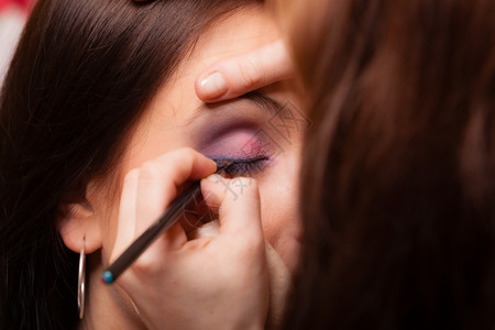 女美貌化妆艺术家的造型师在年轻女眼皮上用刷子遮住眼睛图片