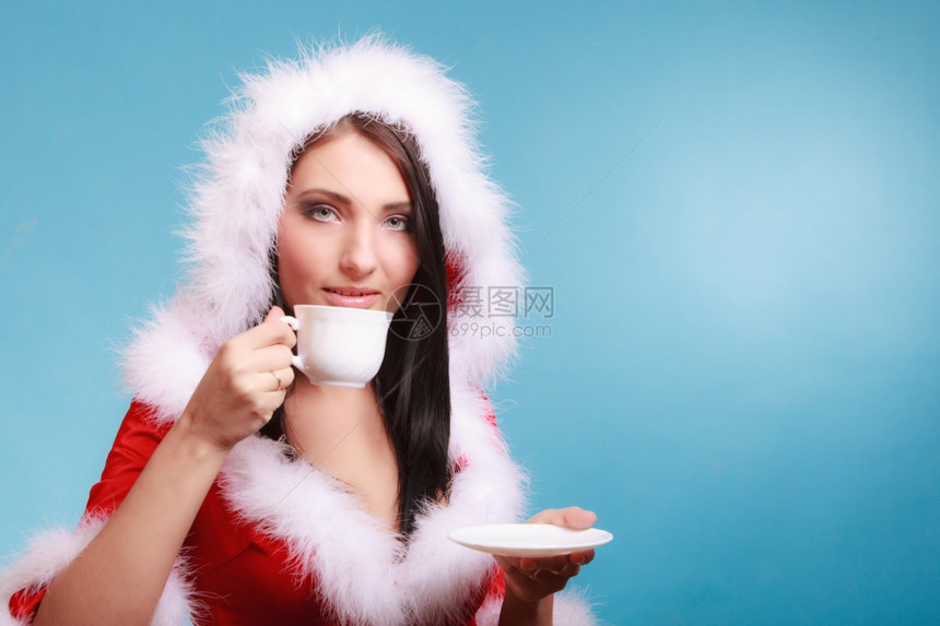 穿着圣达克萨斯服装的漂亮感女人拿着一杯热饮料享受蓝底咖啡时间图片