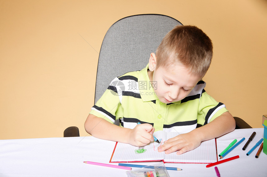 在橙色背景上画彩铅笔的小男孩图片
