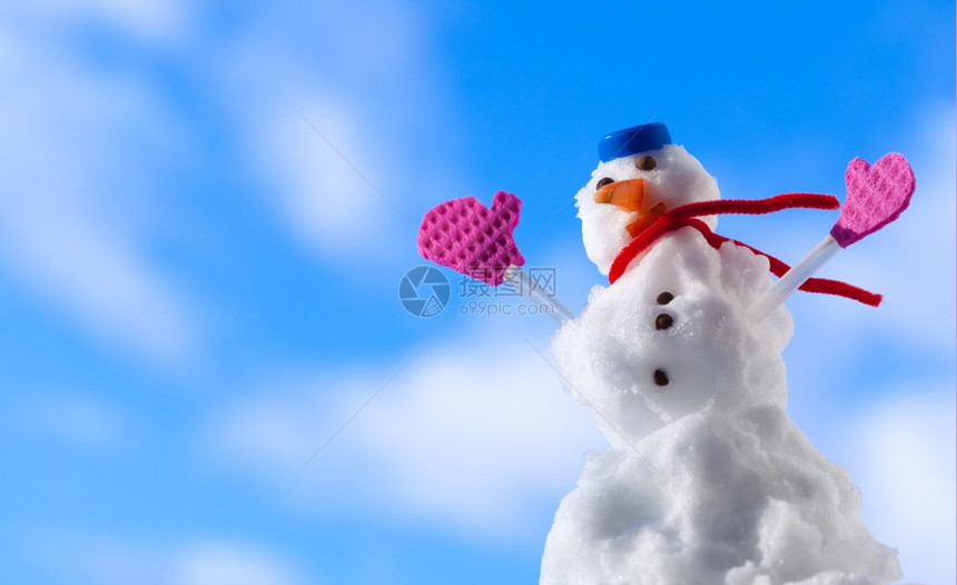圣诞小雪人穿着蓝螺丝顶的色帽子红围巾和粉手套露天冬季节特别蓝天空背景图片