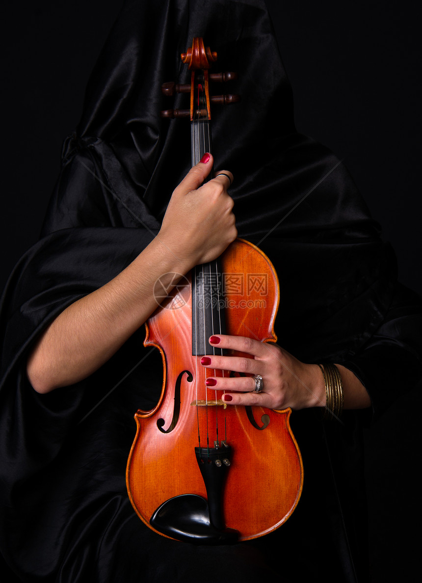 穿黑衣服的女人拿着她珍宝的小提琴乐器图片