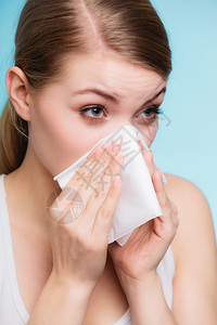 流感或过敏症状生病的女人在蓝色组织里打喷嚏健康护理图片