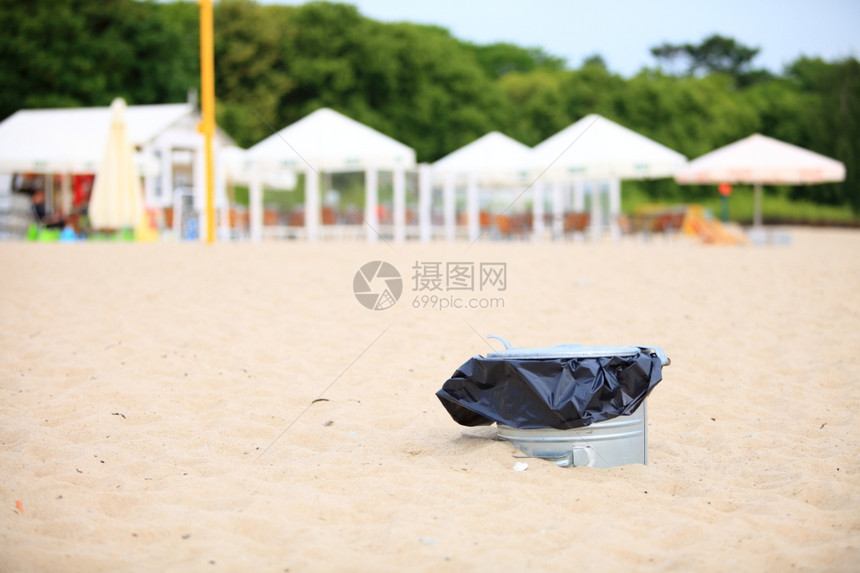 在户外海滩内装塑料袋的灰金属垃圾桶或图片