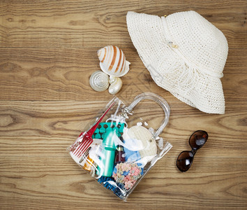 门外装具放在生锈木板上包括清晰的塑料袋梳子太阳屏幕头发剪片海壳太阳眼镜和白帽子项目高清图片素材
