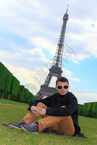 年轻人潮坐在法国巴黎Eiffel塔LaTourEiffel附近的PampdeMars的铁冠上背景图片
