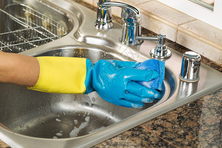 在厨房水池内用海绵和肥皂水清洗手戴橡胶套的近身水平图像图片