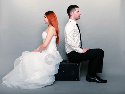 幸福的已婚夫妇红发新娘和郎的肖像坐在旧手提箱上坐在后面的工作室拍摄灰色背景蜜月和旅行微笑高清图片素材