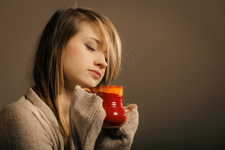 喝热饮沉睡的姑娘拿着一杯茶或咖啡穿着暖毛衣的女人自己暖身子橙色高清图片素材