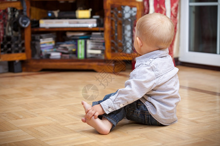 快乐的童年坐在地板上的所有小男孩的背部室内家里背景图片
