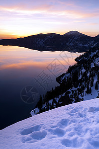 太阳升起照亮火山口湖的场景图片