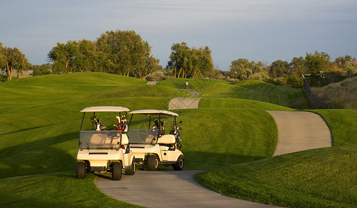 两辆高尔夫球车站在第九洞旁的路上图片