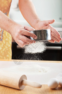 人手用把面粉擦透用来烘烤的筛子图片