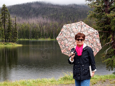 在黄石公园湖附近持有伞子的老年妇女形象图片