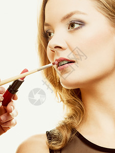 化妆师将口红和配件工具应用到女嘴唇上背景图片