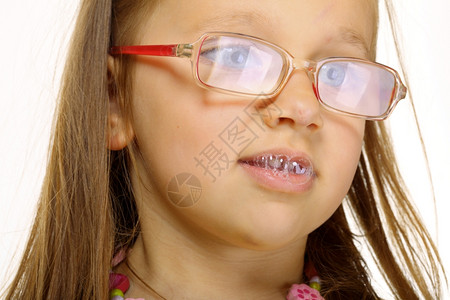 戴眼镜的有趣小女孩吐有趣的唾液泡图片