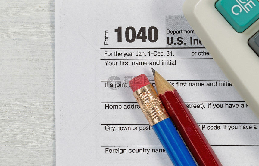 关闭美国个人税表104使用部分旧的计算器和木制桌面上的铅笔专注于图片