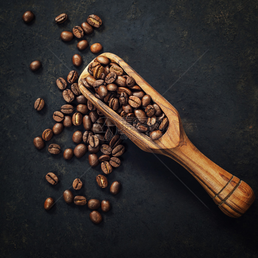 咖啡豆和黑背景的旧木勺子图片