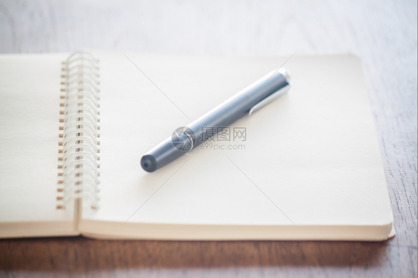 空白螺旋日记本上放着一支笔图片