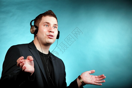 听音乐蓝背景的带耳机男青年学生图片