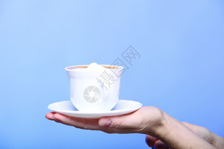 在秋冬时握着一杯拿铁咖啡卡布奇诺热饮的紧女手复制蓝色背景喝高清图片素材