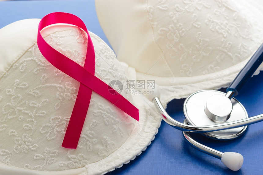 保健医学和乳腺癌认识概念在蓝色背景下女胸罩上贴粉色丝带听诊器图片