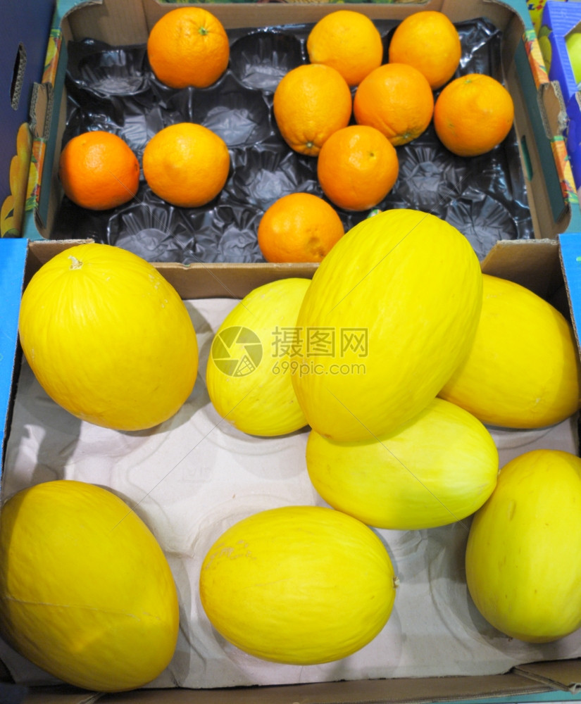 有很多瓜和橘子放在一个盒的市场图片