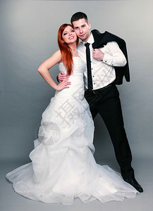 新郎和红发娘的肖像整个工作室里的新郎和红发娘灰色背景拍摄已婚的高清图片素材