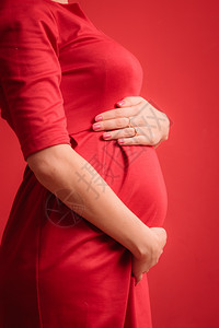 新生命概念怀孕母亲和幸福关紧孕妇肚子穿着时尚优雅的室内红礼服背景图片
