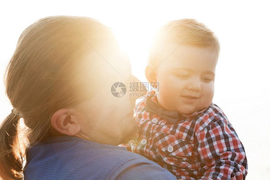 年轻父亲在海滩肖像上抱着孩子儿和父母的纽带图片