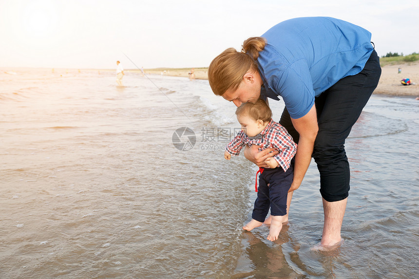 年轻父亲在海水中抱着孩子玩得开心图片