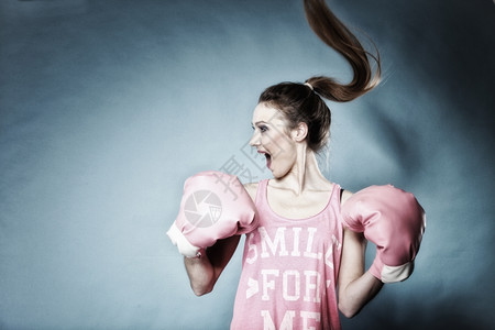 女拳手模型具有大趣的粉红手套玩运动拳打发型蓝背景背景图片