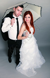 新郎和红发娘的肖像伞式工作室在灰色背景上拍摄时尚高清图片素材